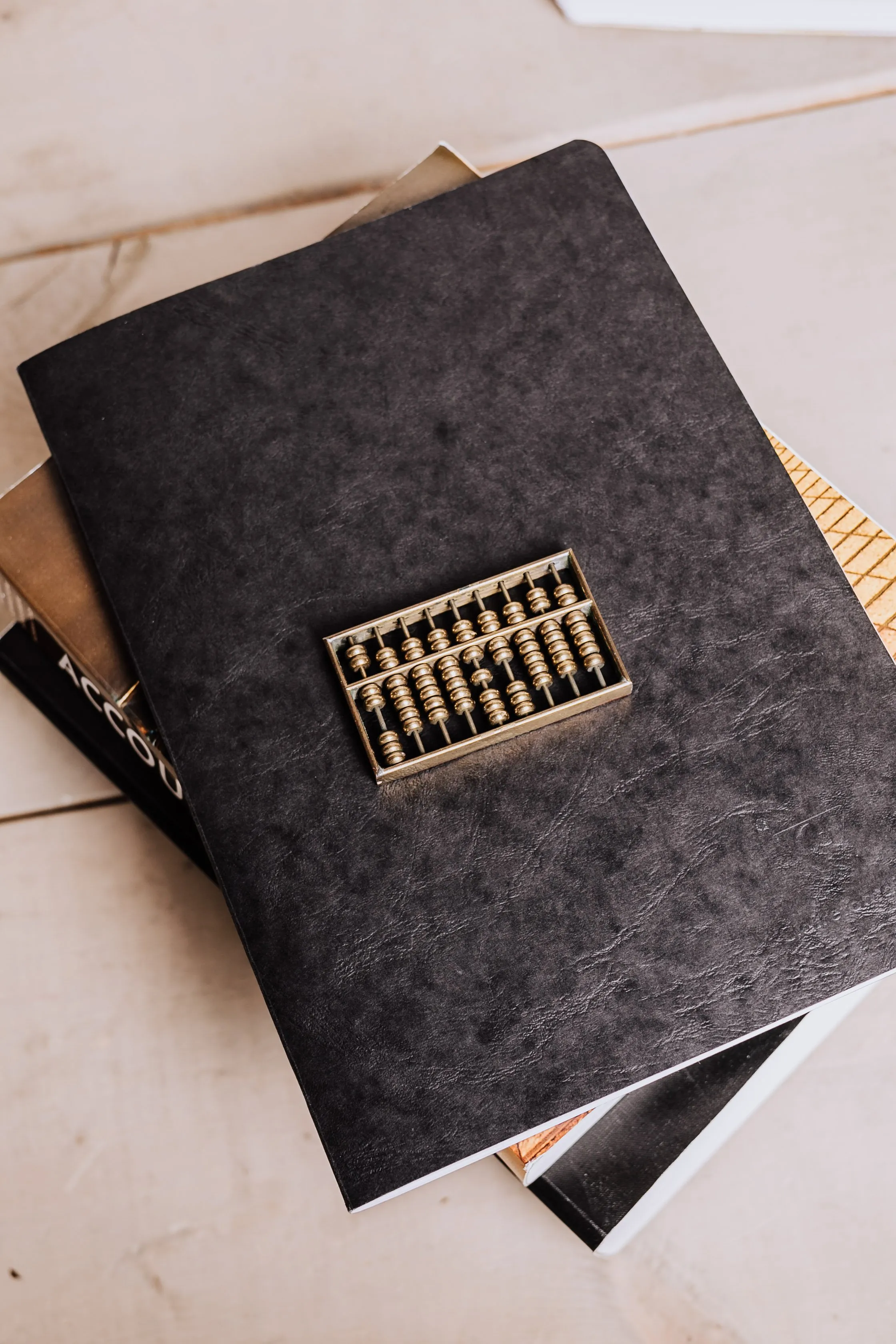 A black notebook with a small brass abacus resting on it